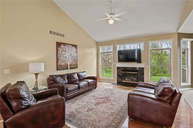 living room with a ceiling fan, wood finished floors, a fireplace, and high vaulted ceiling