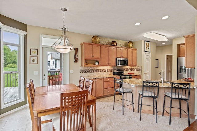 kitchen with stainless steel appliances, tasteful backsplash, a peninsula, a kitchen breakfast bar, and light stone counters