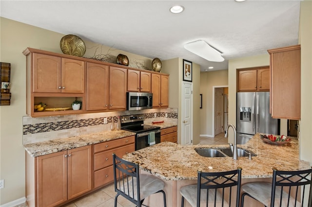 kitchen with appliances with stainless steel finishes, a sink, a peninsula, and a breakfast bar