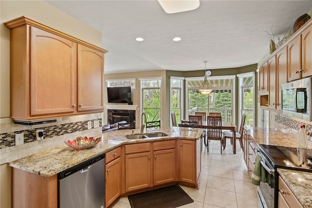 kitchen with stainless steel appliances, a sink, a peninsula, backsplash, and light stone countertops