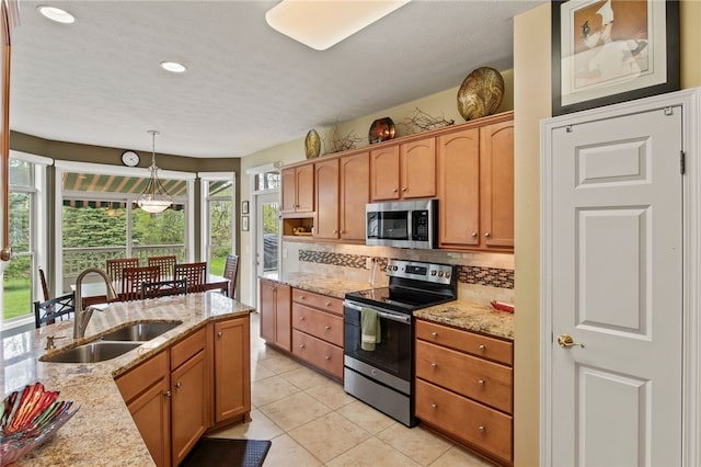 kitchen with appliances with stainless steel finishes, a sink, healthy amount of natural light, tasteful backsplash, and recessed lighting
