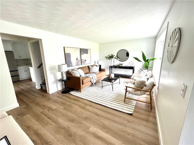 living room featuring wood finished floors, baseboards, and stairs
