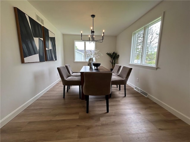 dining space featuring a chandelier, wood finished floors, and baseboards