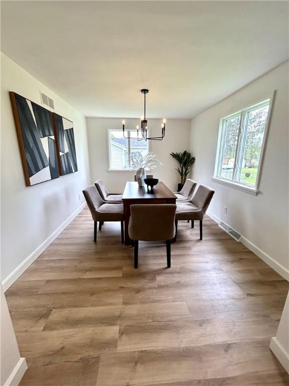 dining room with a chandelier, light wood-style floors, and baseboards