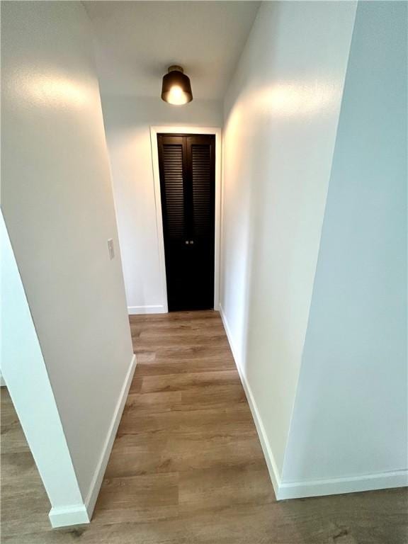 corridor featuring baseboards and light wood finished floors