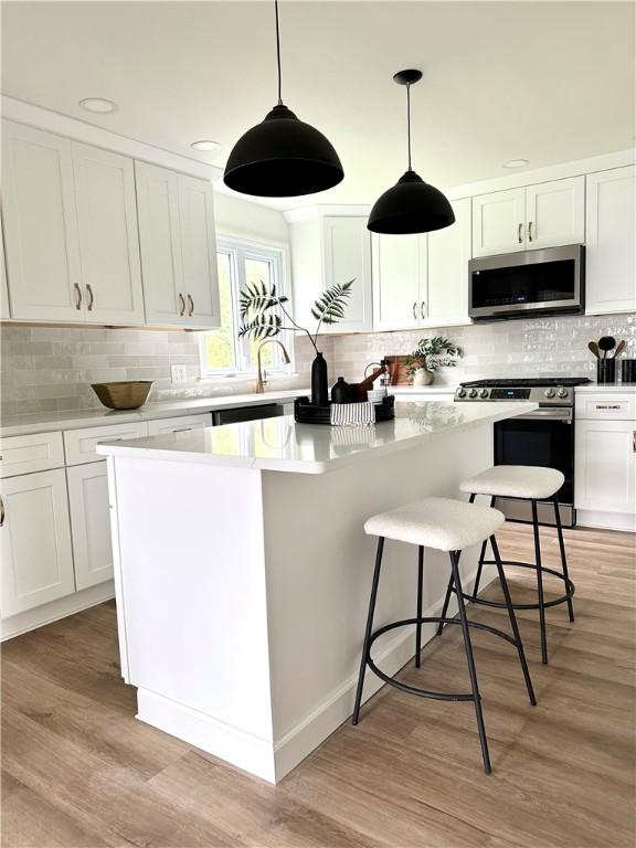 kitchen featuring stainless steel appliances, decorative backsplash, white cabinets, and a center island