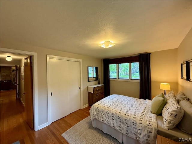 bedroom featuring wood finished floors, baseboards, and a closet