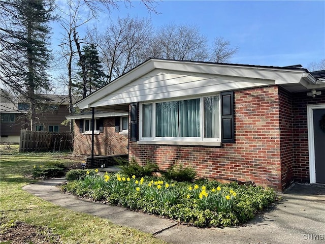 view of side of home with brick siding and fence