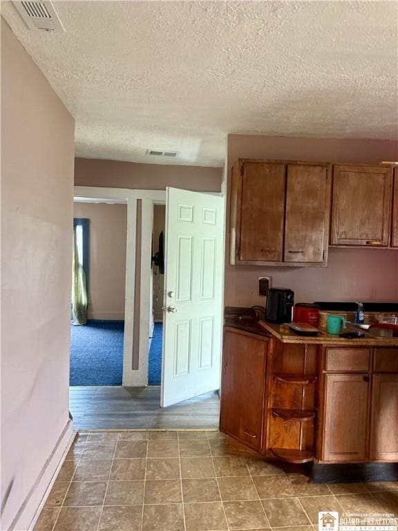 99 King St, Dunkirk-City, NY 14048 - kitchen with a textured ceiling, brown cabinetry, and dark countertops