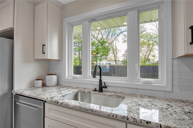 kitchen with a sink, appliances with stainless steel finishes, decorative backsplash, and white cabinets
