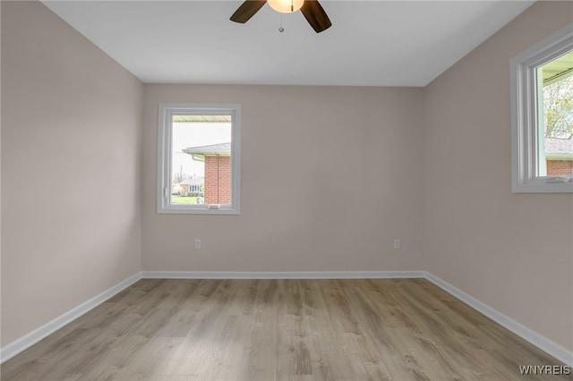 unfurnished room with light wood-style floors, a ceiling fan, and baseboards