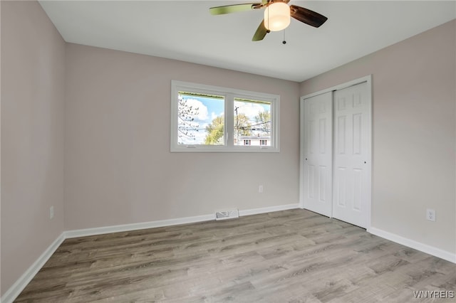 unfurnished bedroom featuring baseboards, wood finished floors, a closet, and ceiling fan