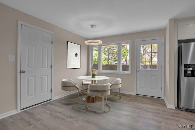 dining space featuring light wood-style floors and baseboards