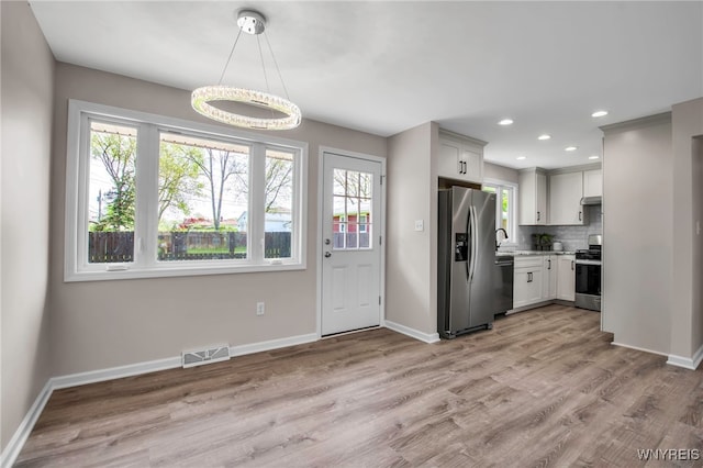 kitchen with stainless steel appliances, a sink, baseboards, light wood finished floors, and recessed lighting