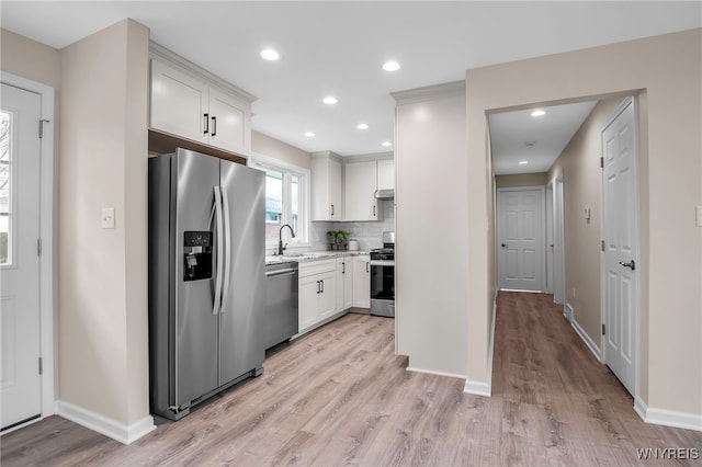 kitchen featuring stainless steel appliances, light wood-style floors, baseboards, a sink, and recessed lighting