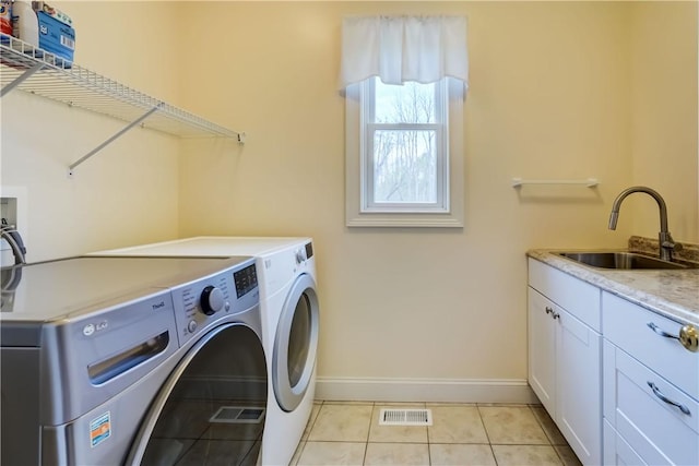 laundry room featuring washer and clothes dryer, baseboards, light tile patterned floors, and cabinet space
