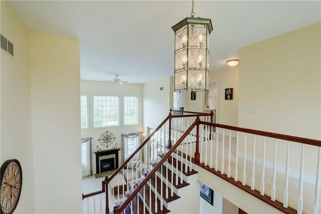 staircase with a ceiling fan and a fireplace