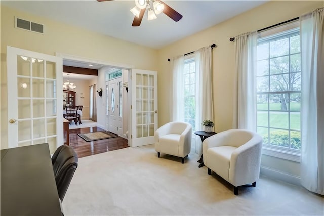 living area featuring plenty of natural light, a chandelier, ceiling fan, and baseboards