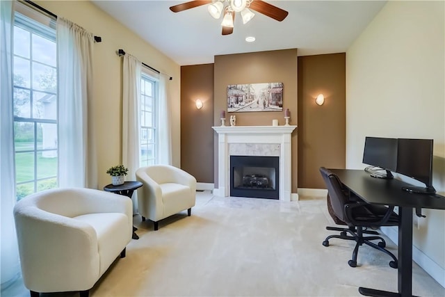 carpeted home office with a ceiling fan, baseboards, and a fireplace