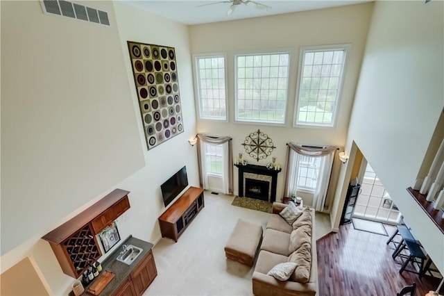 living room featuring a high end fireplace, a high ceiling, and ceiling fan