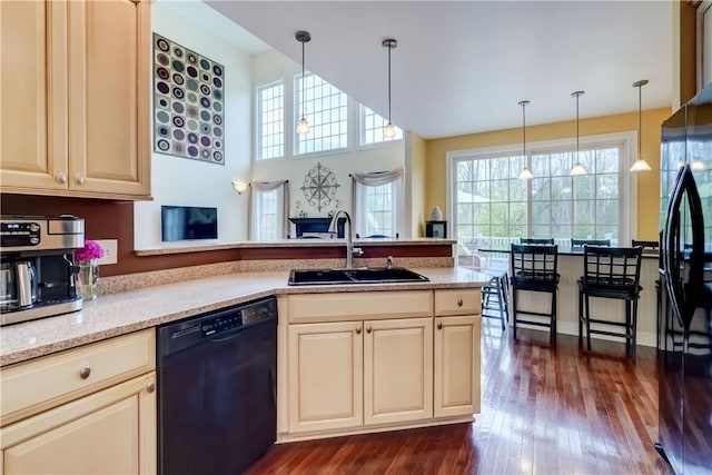 kitchen with black appliances, a sink, cream cabinetry, and plenty of natural light
