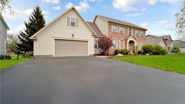view of front of home featuring a garage, a front yard, and asphalt driveway
