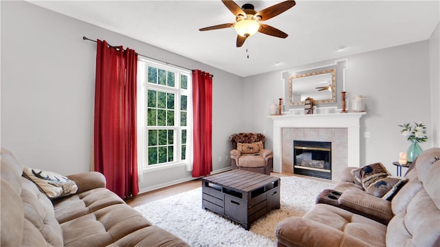 living area featuring a ceiling fan, light wood-type flooring, a fireplace, and baseboards