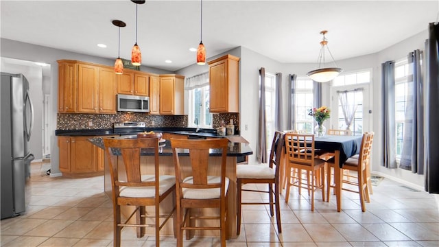 kitchen with stainless steel appliances, dark countertops, light tile patterned floors, decorative backsplash, and a sink