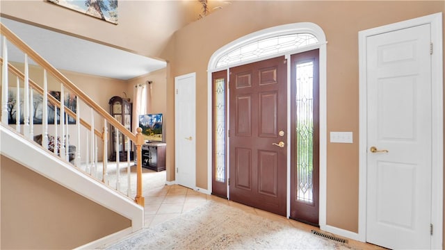 tiled entrance foyer with stairs and baseboards