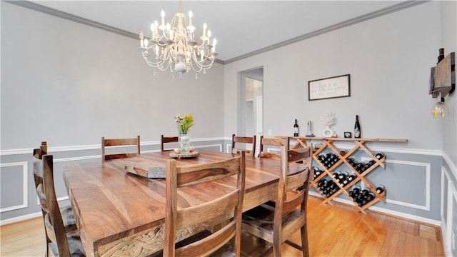 dining room with a chandelier, light wood-type flooring, crown molding, and baseboards