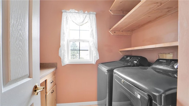clothes washing area featuring independent washer and dryer and cabinet space