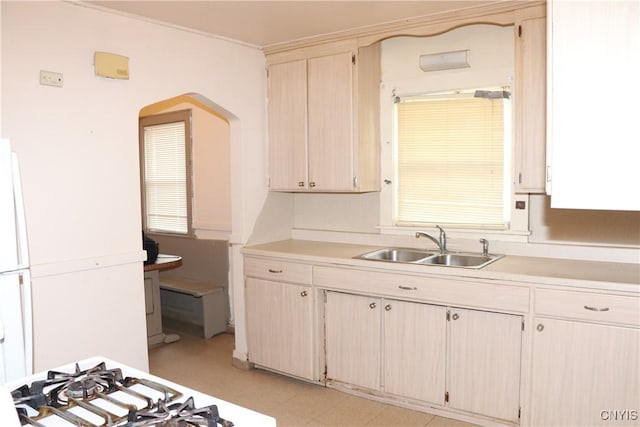 kitchen with light countertops, a sink, light floors, and arched walkways