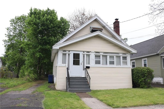 view of front of house featuring entry steps, a chimney, and a front yard