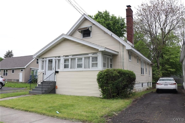 bungalow-style house featuring a chimney, a front yard, and entry steps