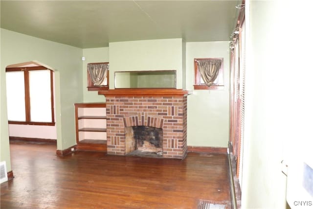 unfurnished living room featuring wood finished floors, baseboards, and a fireplace