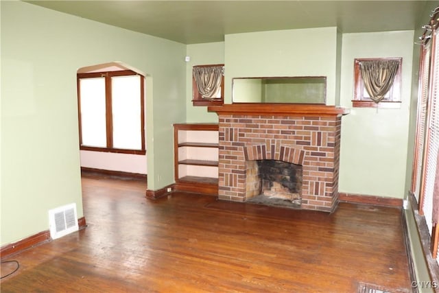 unfurnished living room with baseboards, wood finished floors, and a fireplace