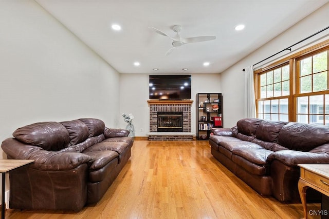 living area featuring ceiling fan, light wood-style flooring, recessed lighting, a brick fireplace, and baseboards