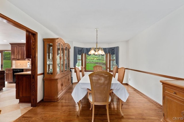 dining room featuring a chandelier, baseboards, and light wood-style floors