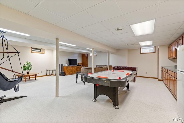 recreation room featuring a drop ceiling, baseboards, and light carpet