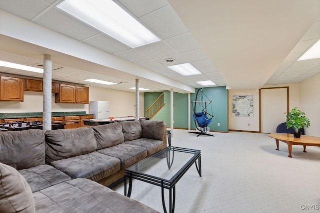 living room with light carpet, a paneled ceiling, and baseboards