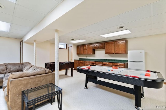 recreation room with a paneled ceiling and light carpet