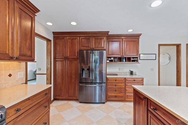kitchen with stainless steel refrigerator with ice dispenser, light countertops, recessed lighting, decorative backsplash, and brown cabinets