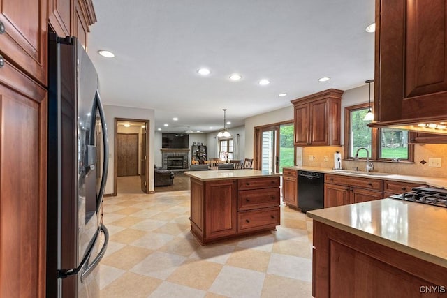 kitchen with a sink, dishwasher, refrigerator with ice dispenser, open floor plan, and hanging light fixtures