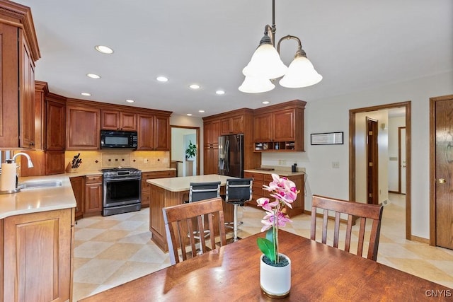 kitchen featuring black appliances, a sink, light countertops, decorative backsplash, and recessed lighting