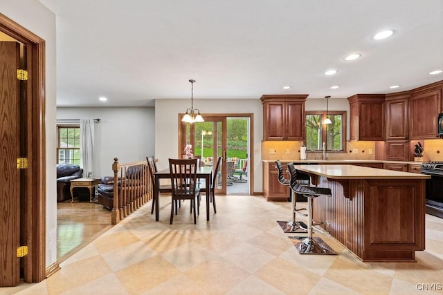 kitchen with light countertops, healthy amount of natural light, backsplash, recessed lighting, and stainless steel range with gas stovetop