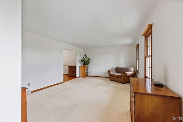 living area featuring light colored carpet and baseboards