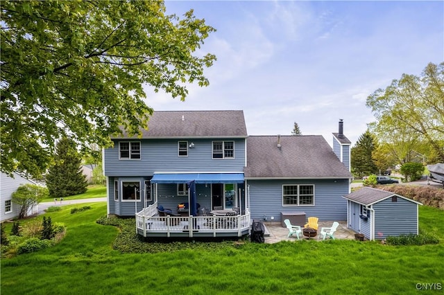 back of house featuring a fire pit, a yard, a deck, an outbuilding, and a storage shed