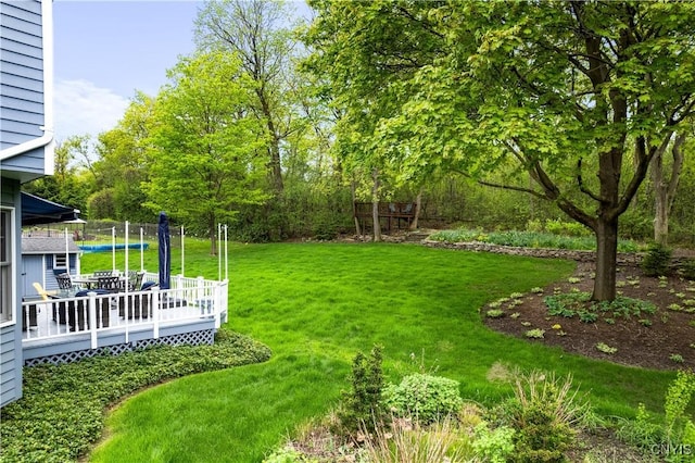 view of green lawn with a wooden deck