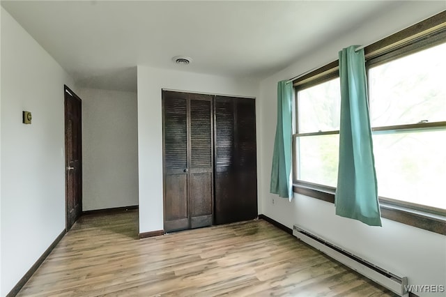 353 Campbell Rd, Sweden, NY 14420 - unfurnished bedroom with baseboard heating, light wood-style floors, a closet, and baseboards