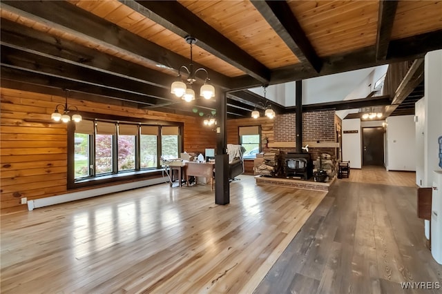353 Campbell Rd, Sweden, NY 14420 - living room featuring a wood stove, wooden walls, baseboard heating, a chandelier, and hardwood / wood-style floors